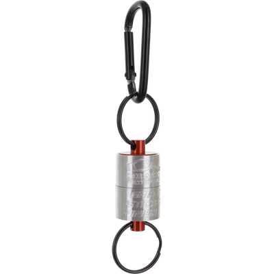 A metallic cylindrical Drake Finisher Magnetic Retractor for waterfowl hunting, featuring orange accents and split rings attached to a black carabiner.