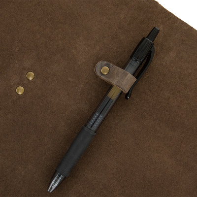 Drake Leather Wingshooters Hunting Log features a brown suede cover with brass rivets, a leather strap, and a pen-holder loop securing a black ballpoint pen.