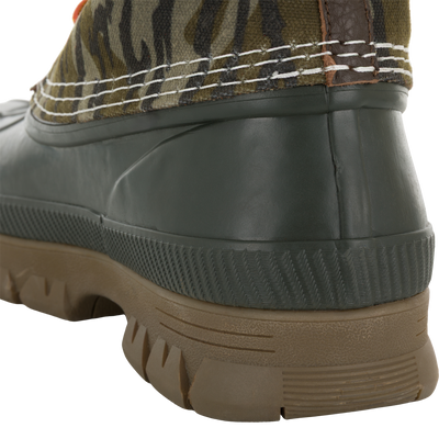 Close-up of the Throwback 80 Waxed Canvas Lace Up Duck Boot, highlighting its camouflage-patterned fabric upper, chunky brown lug tread, and dark green molded rubber heel.