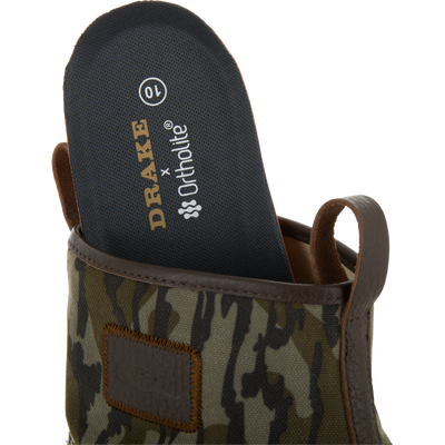 Close-up of a camouflage-patterned Drake x Ortholite insole being placed into the Throwback 80 Waxed Canvas Slip On Duck Boot, highlighting its removable feature.