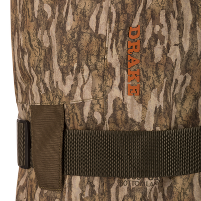 Close-up of Drake's Hardline Uninsulated Breathable Wader with camouflage pattern, featuring an adjustable belt, brand logo, and durable 3-layer waterproof fabric with front cargo pouch.