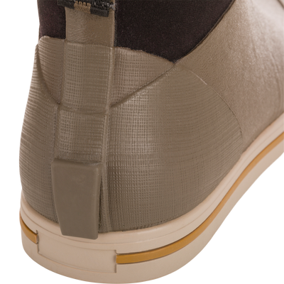 Close-up of Camp Deck Boot's heel, showcasing its olive-taupe waterproof rubber with textured grid, beige outsole, and ochre stripe, ideal for outdoor adventures.