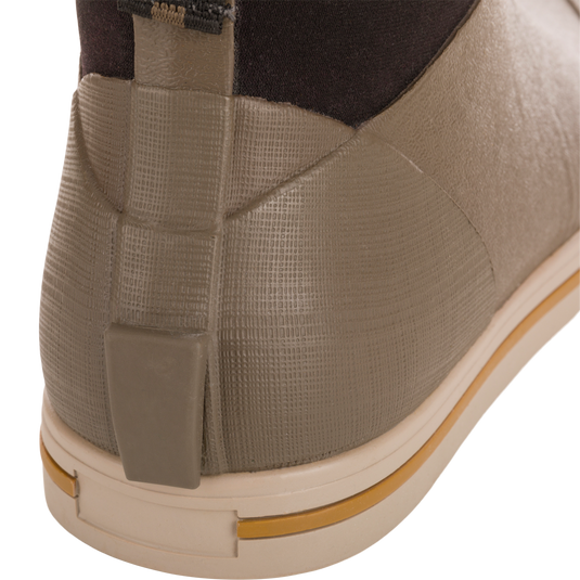 Close-up of Camp Deck Boot's heel, showcasing its olive-taupe waterproof rubber with textured grid, beige outsole, and ochre stripe, ideal for outdoor adventures.
