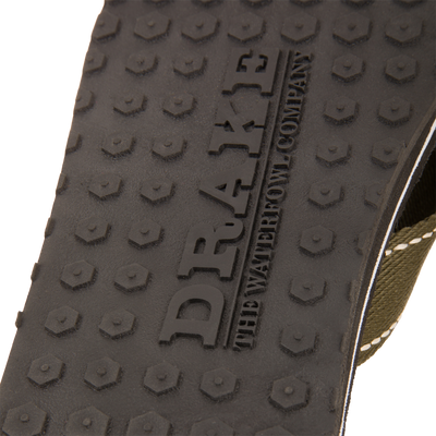 Close-up of Lake Shore Flip Flops' rubber tread with hexagonal pattern and embossed DRAKE, featuring olive-green strap edge, ideal for water adventures.