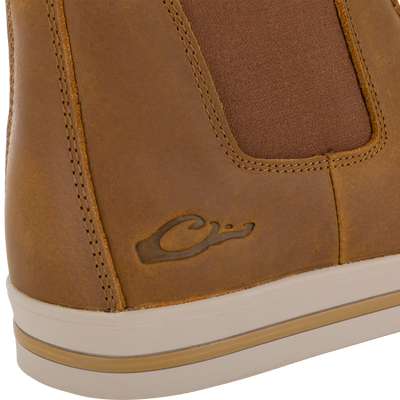 Close-up of a tan Leather Camp Deck Boot with a brown elastic side panel, a rubber sole, and an embossed duck logo on the side.