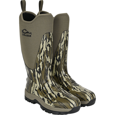 The Waterfowl Uninsulated 16″ Camp Boot in Mossy Oak Original Bottomland features rugged black outsoles, neoprene uppers, pull-on loops, and displays the Drake logo on the side.