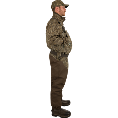 Uninsulated Guardian Elite HND Front Zip Waders: A man turned to the side wearing waders with Internal handwarmer pockets to keep your hands warm and protected on even the coldest days .