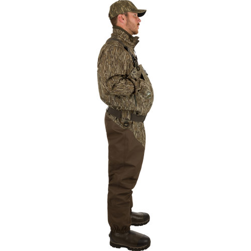 Uninsulated Guardian Elite HND Front Zip Waders: A man turned to the side wearing waders with Internal handwarmer pockets to keep your hands warm and protected on even the coldest days .