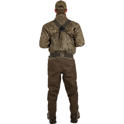 A man in camouflage clothing wearing the Guardian Elite Hybrid Insulated Front Zip Wader, showcasing its advanced features for serious outdoor activities.