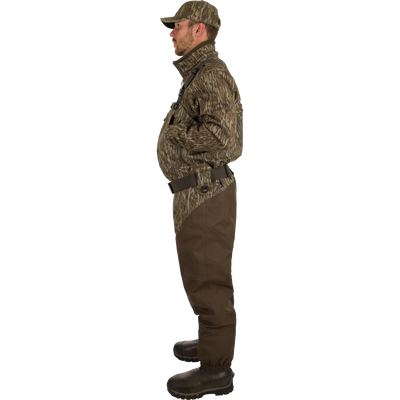 Man wearing Insulated Guardian Elite HND Front Zip Wader- Mossy Oak Shadow Grass Habitat, featuring reinforced seams and Thinsulate® boot lining for warmth and durability in cold weather hunting.