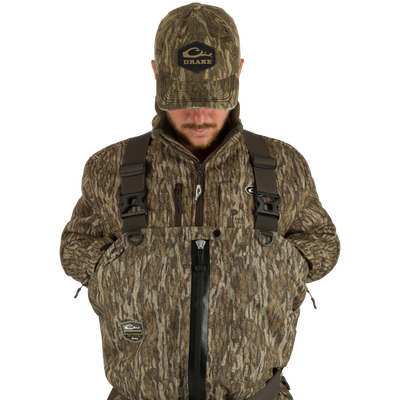 Man wearing Insulated Guardian Elite HND Front Zip Wader, featuring a camouflage jacket and hat, designed for warmth, durability, and waterproof protection.