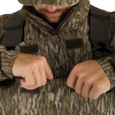 A man wearing Uninsulated Guardian Elite Vanguard Breathable Waders showcasing the front cargo pouch.