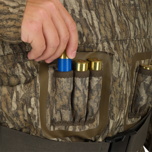 A person inserting a blue and gold bullet into the Uninsulated Guardian Elite Vanguard Breathable Wader vertical shell loops.