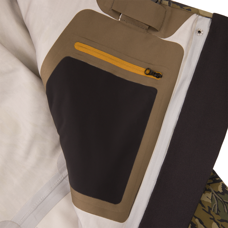 Inner panel of the BMF1600 Kevlar Wader with Primaloft, featuring off-white, tan, and black lining, yellow zip pocket, and camo fabric edge.