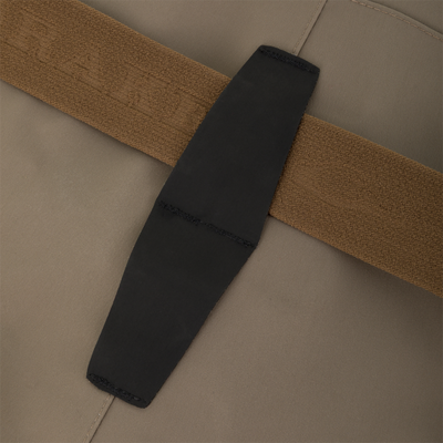 Close-up of a brown elastic strap crossing over a vertical black rectangular patch on tan Kevlar fabric of the Drake X Ducks Unlimited BMF1600 Kevlar Wader.