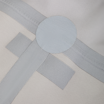 Close-up of a light gray Drake X Ducks Unlimited BMF1600 Kevlar Wader fabric featuring a circular patch and intersecting reinforced webbing straps.