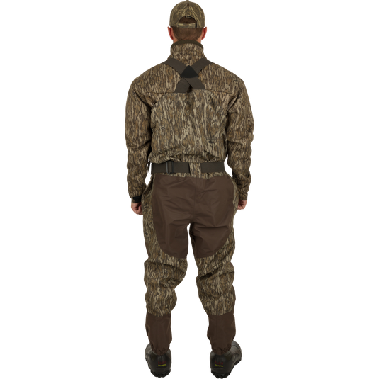 A man in camouflage clothing wearing Insulated Guardian Elite Vanguard Breathable Waders - Realtree, standing in nature.