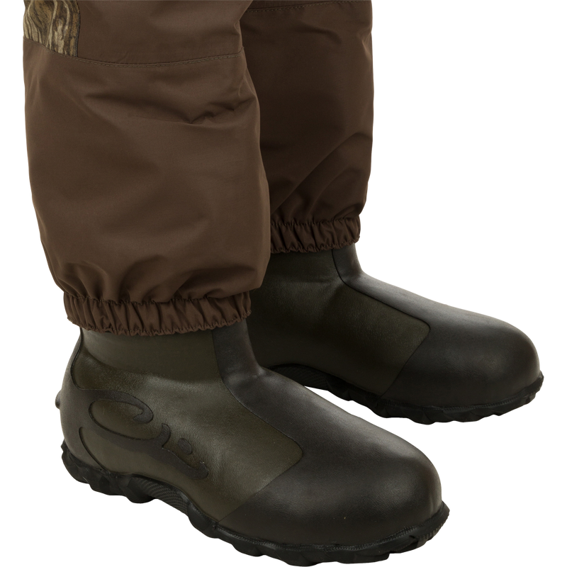 A pair of brown boots with black soles, part of the Insulated Guardian Elite Vanguard Breathable Waders - Realtree collection by Drake Waterfowl.