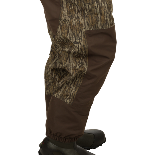 A person wearing Youth Insulated Guardian Elite Vanguard Breathable Waders - Realtree, with camouflage pants, a jacket, and shoes.