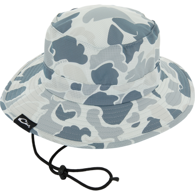 Drake Shoreline Boonie Hat with grey-blue camo pattern, adjustable chin cord, and brand tag, designed for breathability and sun protection with antimicrobial treatment.
