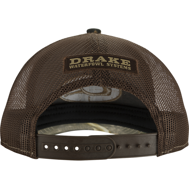 A brown hat with a logo on it, featuring the iconic Drake Head Oval from the Drake Logo Series. Constructed with 100% cotton twill front panels, a tonal polyester mesh back, and a slightly pre-curved visor. Trucker shape with a snapback closure.