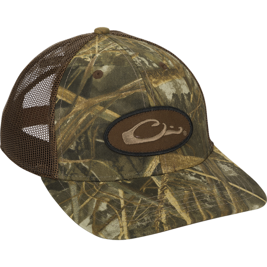 A close-up of the Oval Patch Ranger Camo Mesh Back Cap with a logo on it, featuring a brown patch with a black border and a letter C.