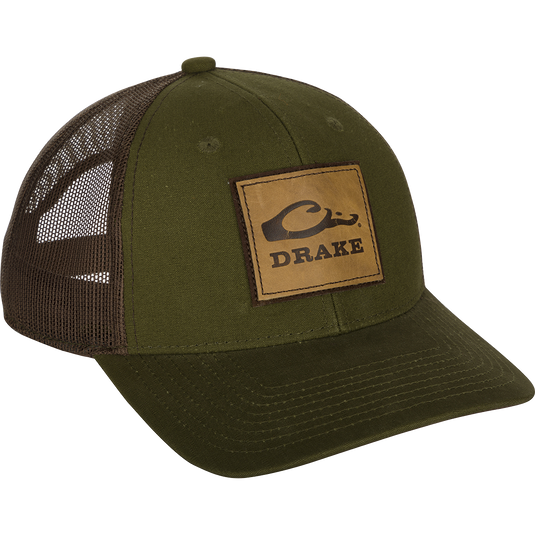 A weathered cotton/poly structured cap with a leather patch featuring the Drake Logo. Traditional trucker shape with a pre-curved visor. Adjustable snap back closure.