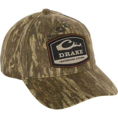 A 6-Panel Badge Cap with a patch on it, featuring a close-up of the patch and logo. Made of cotton blend panels with a rear snap closure. Perfect for outdoor enthusiasts.