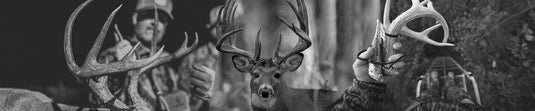 Black and white image of a deer with hunters in the background