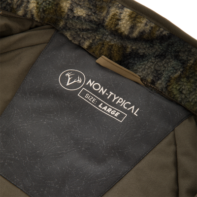 Inside view of the Non-Typical Statix Sherpa Fleece Insulated Jacket, showcasing the camo fleece collar lining and label with antler logo and size information.