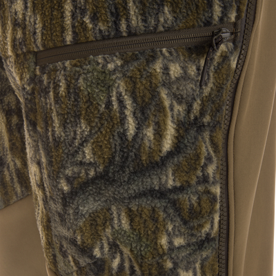 Close-up of Non-Typical Statix Fleece Lined Bib's zippered pocket, showcasing mottled-camouflage sherpa fleece and smooth shell panel, designed for extreme cold hunting conditions.