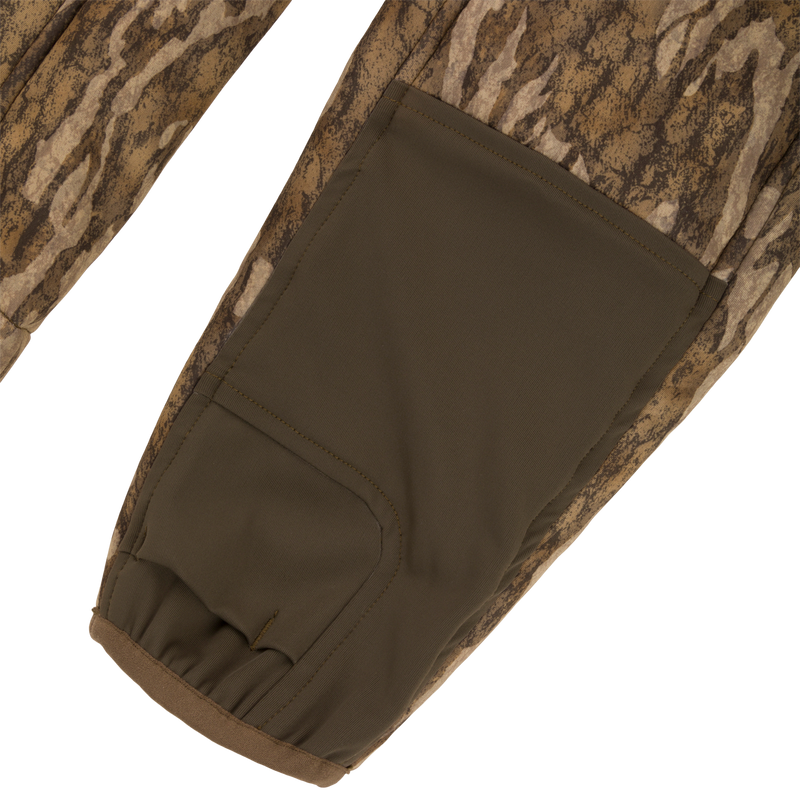 Close-up of a Midweight Nova Silencer Jacket sleeve, showcasing camo pattern and olive-green reinforced panel with elastic cuff, highlighting its versatility and functionality for hunting.