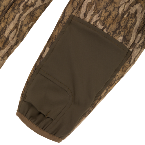 Close-up of a Midweight Nova Silencer Jacket sleeve, showcasing camo pattern and olive-green reinforced panel with elastic cuff, highlighting its versatility and functionality for hunting.