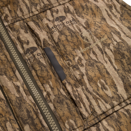 Close-up of the Midweight Nova Silencer Vest with Agion Active X2, featuring a chunky zipper, welted pocket, and Mossy Oak Bottomland camo with brand logos.