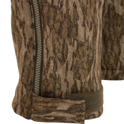 Close-up of Midweight Nova Silencer Bib's camo-patterned leg, featuring a zipper and Velcro strap, designed for warmth, breathability, and scent control in hunting environments.