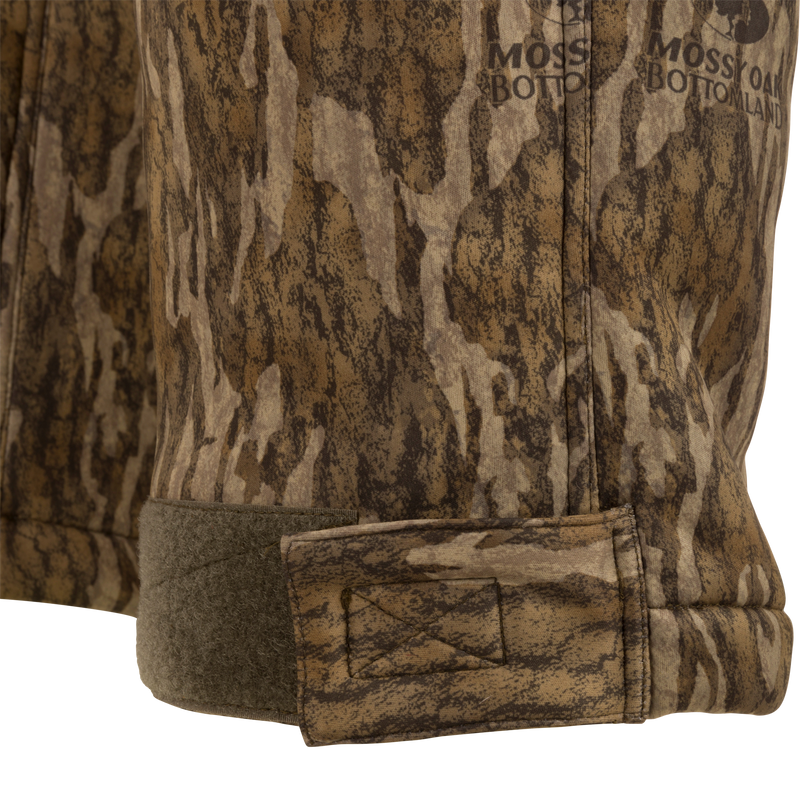 Close-up of the Midweight Nova Silencer Pant's hem, featuring Mossy Oak camo print and adjustable Velcro tab for a snug fit.