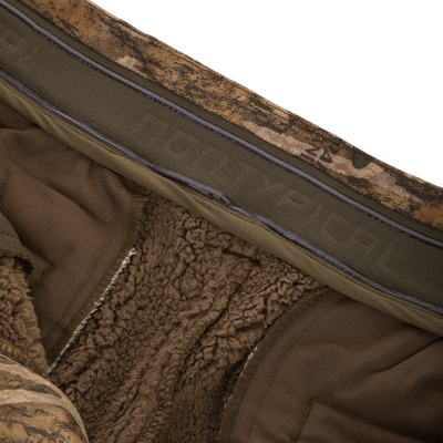 Midweight Nova Silencer Pant with Scent Control featuring brown sherpa lining, non-slip waistband, and camouflage shell, ideal for hunting with anti-odor and water-resistant features.