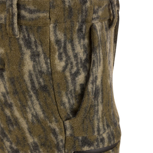 Close-up of Midweight Hydrowool Softshell Pant's hand-warmer pocket, showcasing mottled wool blend fabric with visible zipper, highlighting its utility for outdoor adventures.