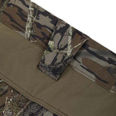 Close-up of a camo boonie hat's brim and branch loop, highlighting the Non-Typical SWT Pant with Scent Control's outdoor gear integration.