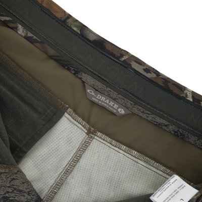 Close-up of Non-Typical SWT Pant with Scent Control interior, showing camo fabric panels, over-lock stitching, elastic band, and tags indicating brand and 100% polyester composition.