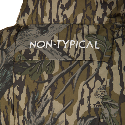 Close-up of the Non-Typical Down Vest with Agion Active X2 by Nontypical, featuring camouflage leaf and branch patterns, “NON-TYPICAL” in white on the back, and a small logo in the lower right corner.
