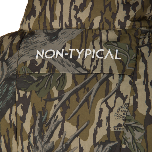 Close-up of the Non-Typical Down Vest with Agion Active X2 by Nontypical, featuring camouflage leaf and branch patterns, “NON-TYPICAL” in white on the back, and a small logo in the lower right corner.