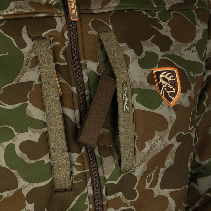 A close-up of the Youth Silencer Full Zip Jacket in full camo pattern with Agion Active XL scent control technology, featuring vertical chest pockets with lanyards for hunting gear.