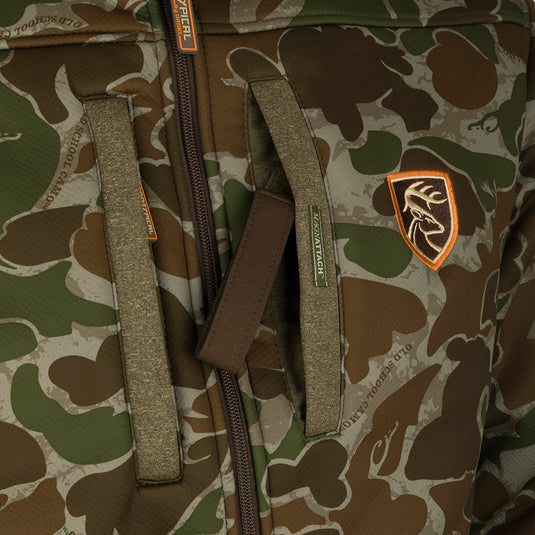 A close-up of the Youth Silencer Full Zip Jacket in full camo pattern with Agion Active XL scent control technology, featuring vertical chest pockets with lanyards for hunting gear.