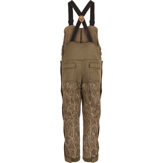 Silencer Bib: camouflage overalls with zippered and Magnattach™ chest pockets, side zippers, and scent control technology, designed for hunting.