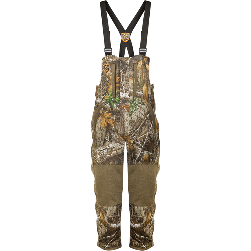A durable camouflage overalls with straps for hunting gear.
