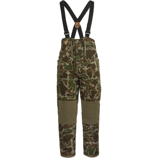 A camouflage pants with suspenders, featuring Agion Active XL® scent control technology. Vertical pockets with lanyards for hunting gear.