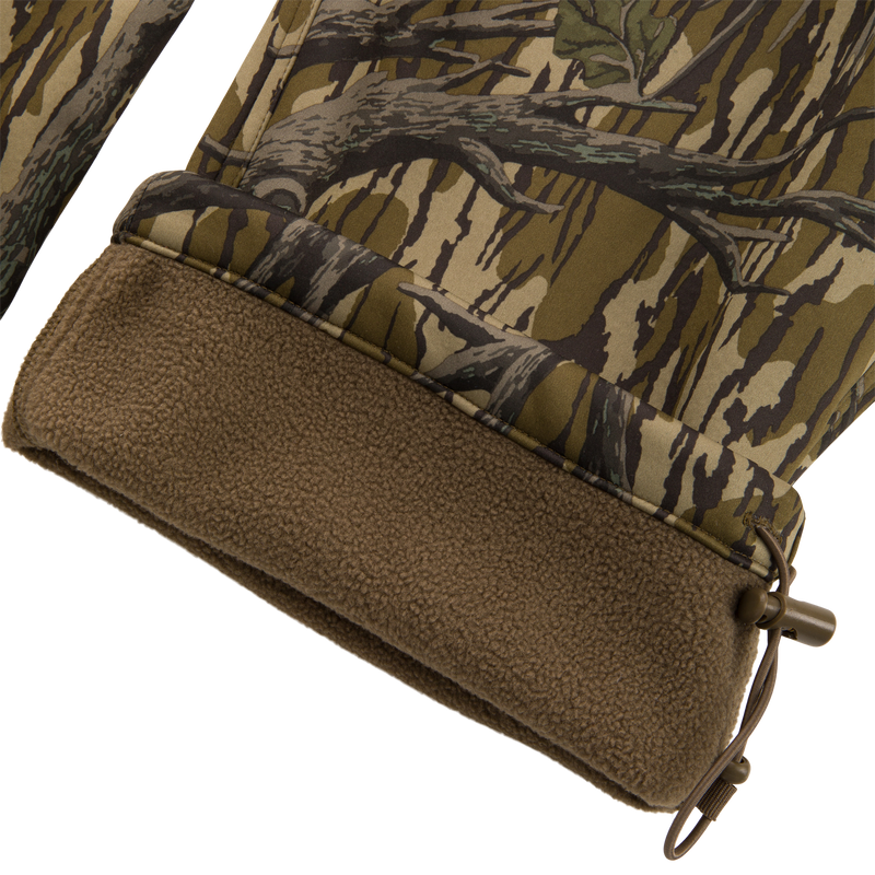 Close-up of Non-Typical Endurance Pant's hem, showing camouflage shell, brown fleece lining, and elastic drawcord with toggle for adjustable fit.