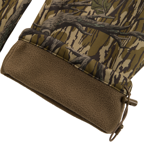 Close-up of Non-Typical Endurance Pant's hem, showing camouflage shell, brown fleece lining, and elastic drawcord with toggle for adjustable fit.