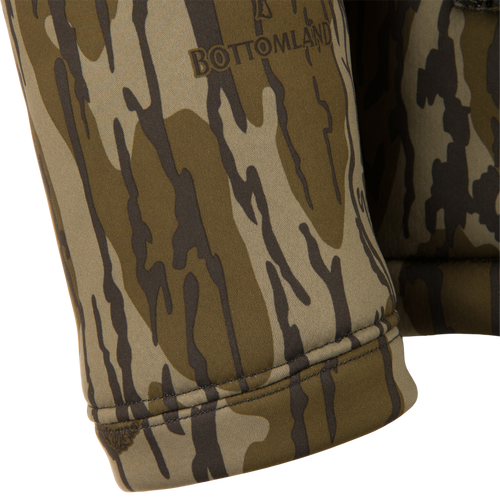 Close-up of BOTTOMLAND logo on Non-Typical Silencer Full Zip Hoodie cuff, showcasing camouflage design and high-quality polyester fleece for warmth and quietness.